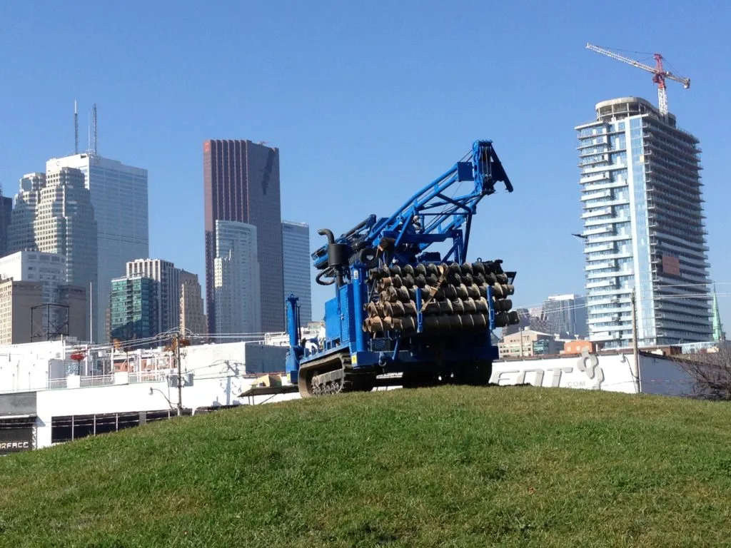 Geo-Environmental Drilling track-mounted drill rig on a rise in front of the Toronto skyline